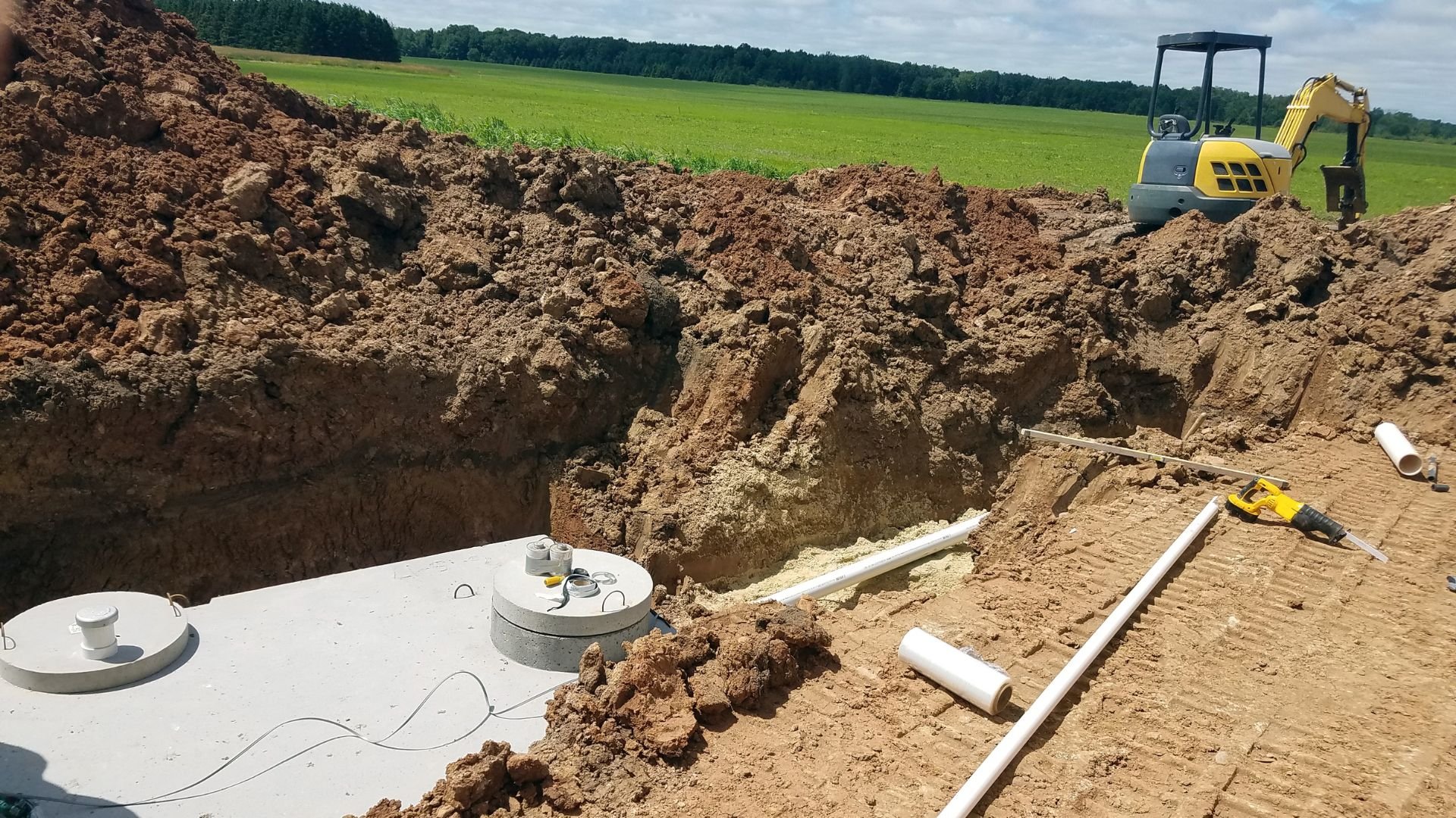 Underground septic tank installation with excavator in rural field