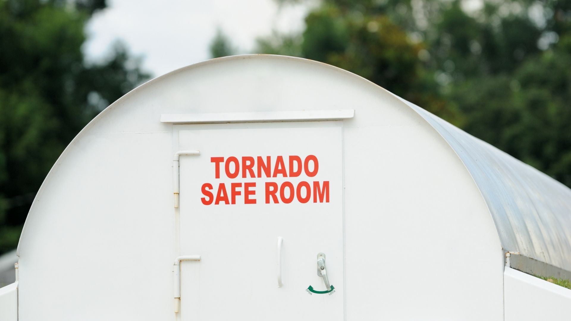 White tornado safe room with red lettering against blurry green background