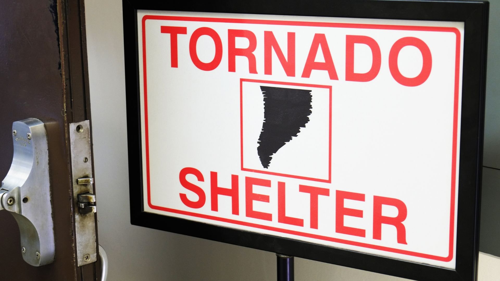 Red and white sign indicating tornado shelter with black tornado icon